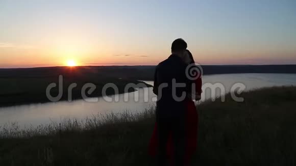 一对相爱的情侣在河边接吻日落的光视频的预览图