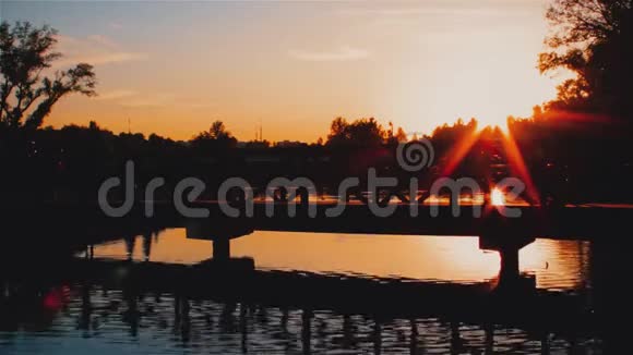 傍晚的风景和日落人们沿着桥在公园里过河视频的预览图