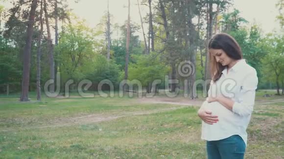 抱着肚子在夏天散步的孕妇视频的预览图