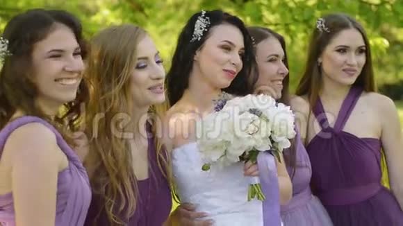 情绪化的新娘和伴娘说话微笑穿紫色裙子在户外摆姿势的白人女孩视频的预览图
