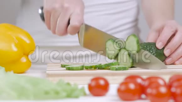 女人在砧板上切绿色黄瓜桌子上有蔬菜视频的预览图