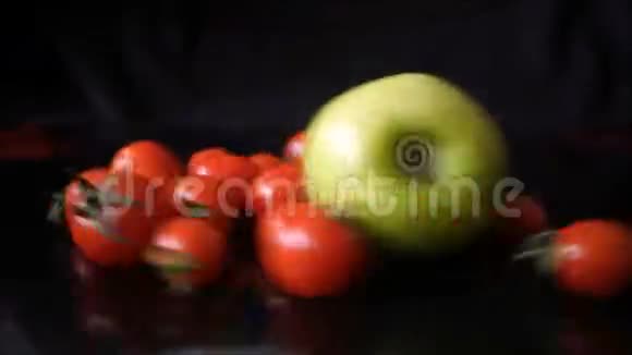 黑色背景下红樱桃西红柿与绿苹果的旋转视频的预览图