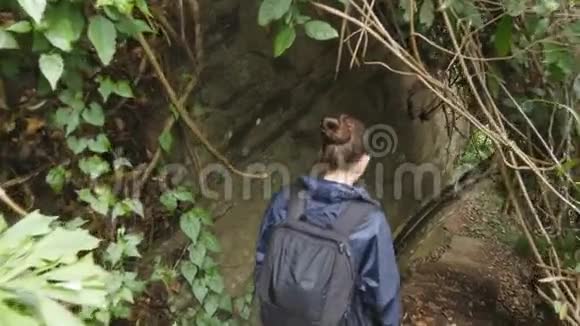 穿着雨衣的小女孩在旅途中从楼梯上走下来带背包在热带徒步旅行的女士视频的预览图