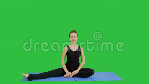 年轻女子在绿色屏幕上练习瑜伽时伸展双腿Chroma键视频的预览图