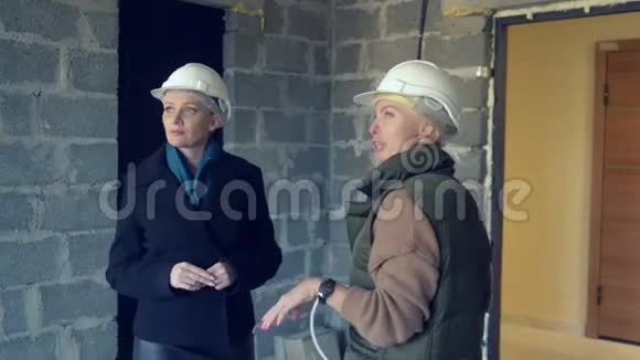 两个戴着白盔的女人在室内粗犷地交谈视频的预览图