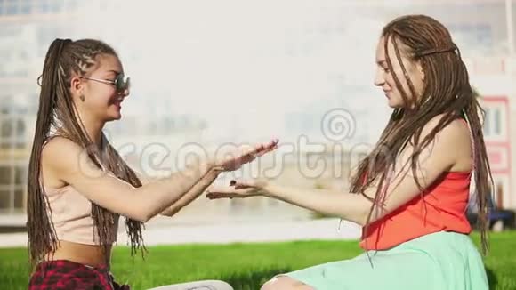 快乐的女人与恐惧坐在草地上夏季公园年轻的朋友在户外聊天和玩耍玩得很开心穆拉特托视频的预览图