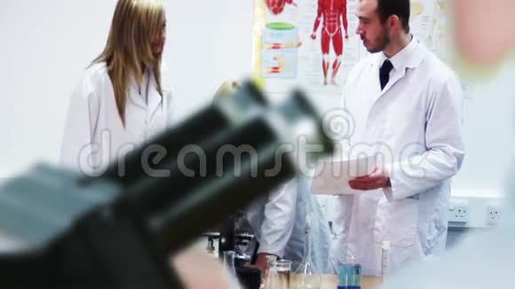 穿着实验室外套的人在看显微镜视频的预览图