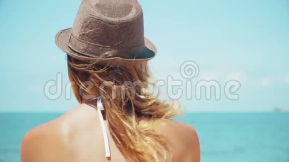 有着巨大太阳帽的女人望着地平线在海洋上缓慢地运动视频的预览图