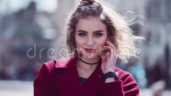 漂亮的年轻女人穿着红色外套抚摸她的头发脸就在相机旁边玩的心情性感一点放松时间视频的预览图