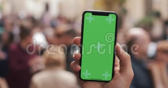 近距离拍摄男子手拿智能手机与绿色屏幕上的城市街道背景铬键视频的预览图