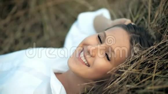 美丽的少女躺在金色的草草里视频的预览图