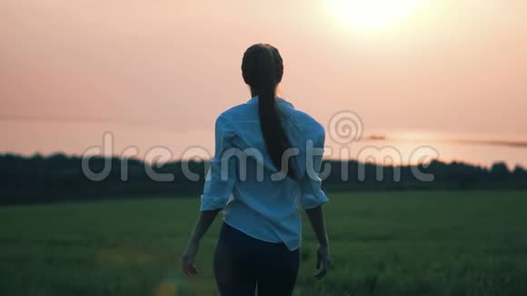 日落时分美丽的年轻女士在田野里散步视频的预览图
