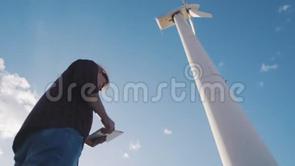 风车发电厂工程师手持平板电脑天空背景视频的预览图