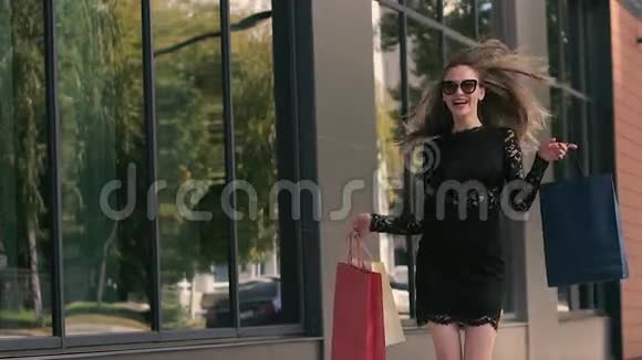 快乐的年轻女子抱着购物袋兴奋地跳起来视频的预览图