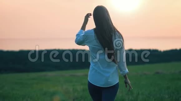 日落时分美丽的年轻女士在田野里散步视频的预览图
