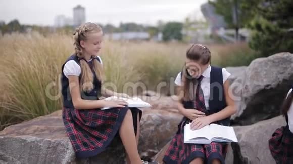 一群穿着相同校服的学生在户外看书时坐着聊天视频的预览图