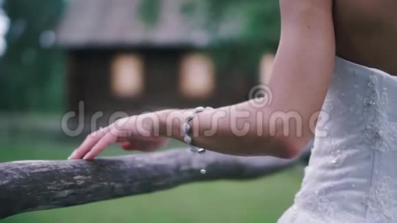 新娘的双手着漂亮的白色婚纱剪辑室外靠近木栅栏的新女孩视频的预览图
