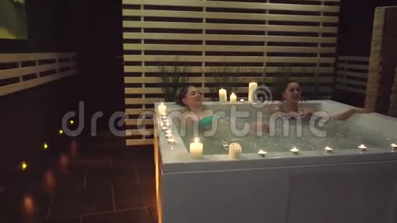 两个快乐的朋友在按摩浴缸里休息在水疗中心饱含海盐视频的预览图