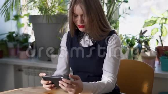 年轻的商业女性在咖啡馆里使用她的智能手机里面有很多绿色植物视频的预览图
