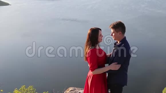 一对相爱的情侣在河边接吻日落的光视频的预览图