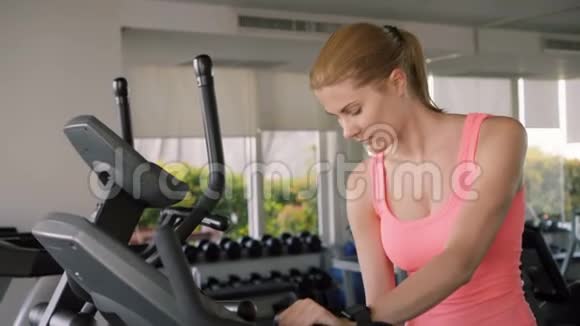 漂亮的适合年轻女子在健身房做运动的天鹅绒模拟器瓶装饮用水视频的预览图