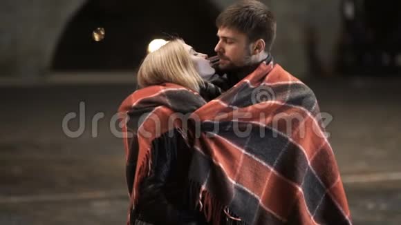 一对年轻夫妇在寒冷的秋夜在城市公园拥抱和亲吻视频的预览图