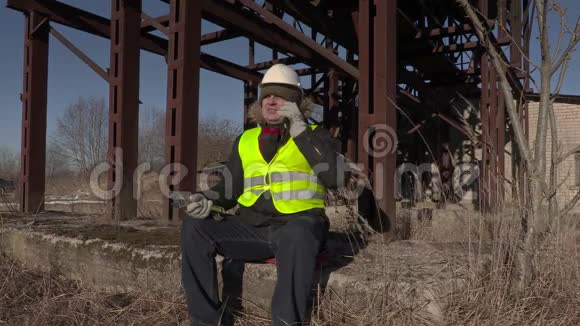 坐在金属罐附近打电话的工人视频的预览图