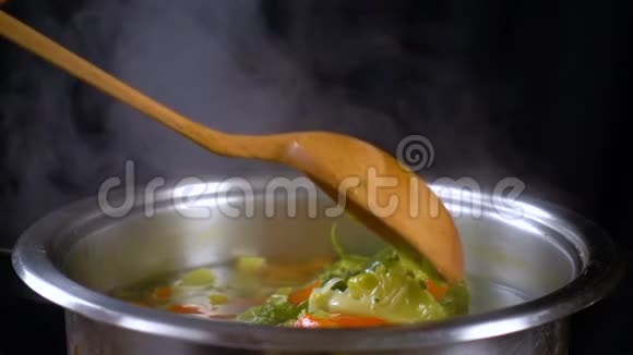 用木勺搅拌蔬菜汤慢动作视频的预览图