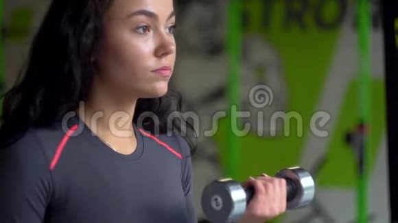 年轻健身女子在健身房用哑铃锻炼视频的预览图