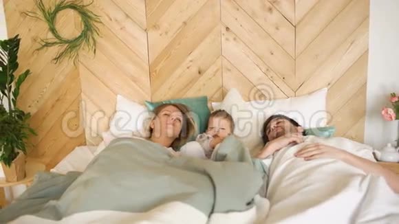 年轻有趣的男孩醒来时他的父母早上睡在他们家的床上视频的预览图