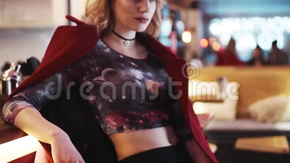 漂亮的欧洲女孩穿着一件红色外套站在酒吧旁边并向相机微笑华丽的视频的预览图