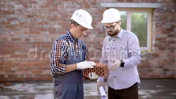 年轻的男建筑工给他的工头展示砖头视频的预览图