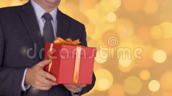 白种人商人持有并赠送红色礼品盒从不聚焦到聚焦运动经典商务套装的成年男子视频的预览图