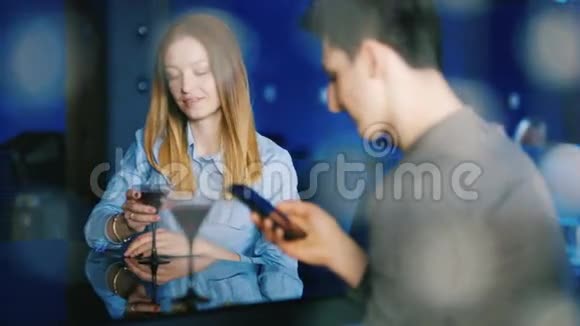 一对年轻夫妇在咖啡馆里休息互相忽视注意电话和互联网视频的预览图