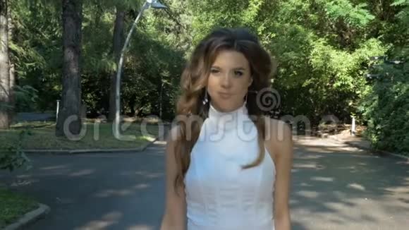 美丽的年轻女子正沿着公园的小路走视频的预览图