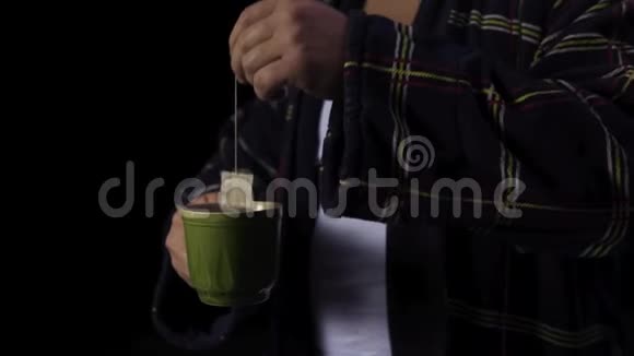 穿着浴袍和一杯茶的人库存一个人在黑色背景上泡茶不良情绪观念视频的预览图