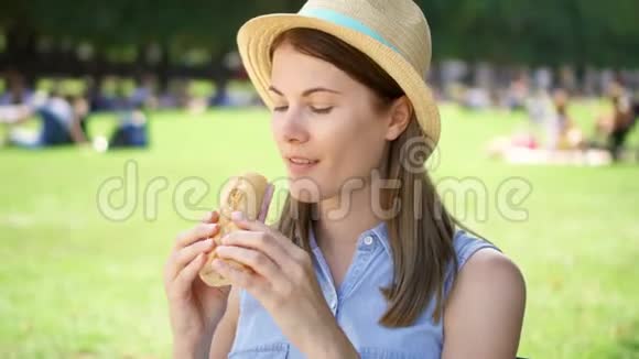 饥饿的女人在公园里吃面包游客在公共公园享用午餐享受夏日阳光视频的预览图