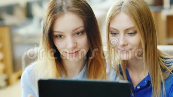 两个年轻迷人的女人在享受平板电脑在阳光明媚的下午坐在咖啡馆里肖像画视频的预览图