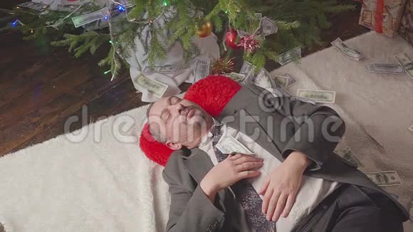 钱落在一个睡在圣诞树旁的人身上视频的预览图