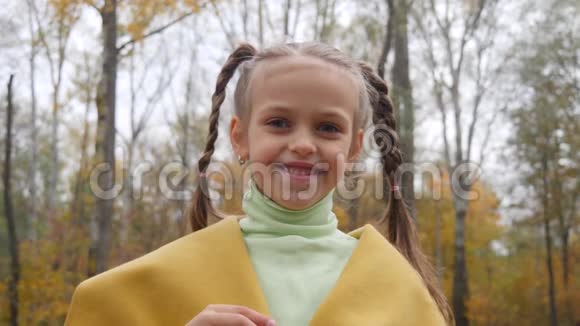 阴天时穿着黄色外套的小女孩在公园里吹气泡视频的预览图