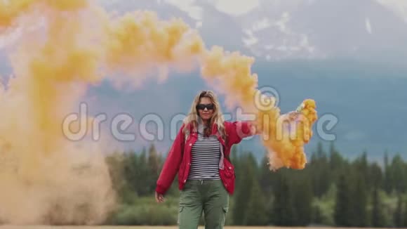 有烟棒的女性旅行者给了一个标志并用彩色烟雾吸引了人们的注意抱着烟的旅游女孩视频的预览图