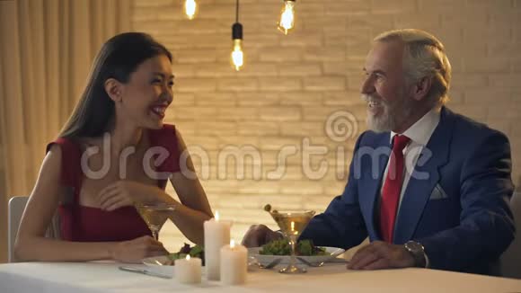 美丽的女士在餐馆里和老富翁笑着调情护送视频的预览图
