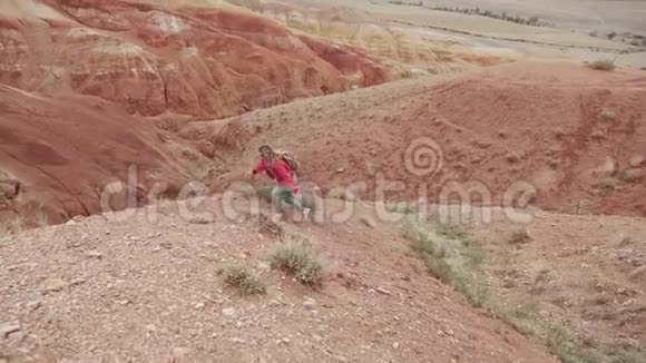 旅行者登上一座陡峭的小山一个背着背包戴着墨镜的旅游女孩走在山区视频的预览图