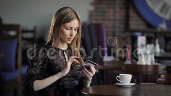 可爱的女性使用信用卡年轻美丽的女性穿着优雅的衣服坐着时使用电话和信用卡视频的预览图