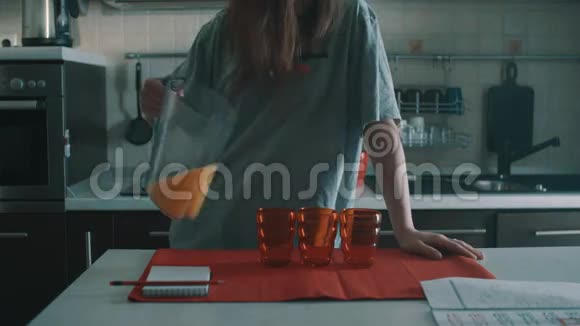 一个棕色头发的女孩把橙汁倒进红色的玻璃杯里溅得到处都是视频的预览图