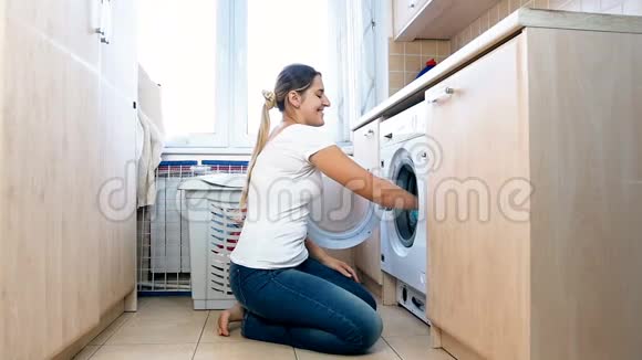 快乐快乐的家庭主妇把干净的衣服扔进洗衣店的慢镜头视频的预览图