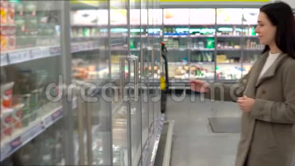 一个年轻的女人在超市里选择和购买乳制品玻璃橱窗酸奶视频的预览图