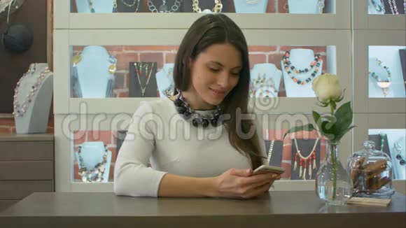 漂亮的女卖家在智能手机上发短信在珠宝店里笑得可爱视频的预览图