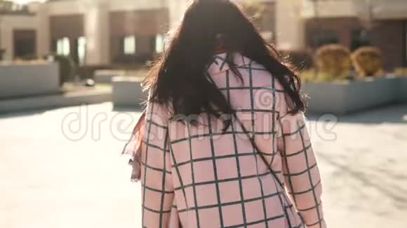 迷人的年轻女子在镜头前嬉戏地转过身穿秋装的女孩有背面的景色那个女孩正在走路视频的预览图