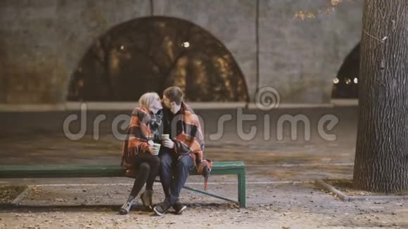 一对年轻夫妇在寒冷的秋夜在城市公园拥抱和亲吻视频的预览图